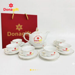 Cận cảnh bộ ấm chén sứ viền vàng in logo DonaGift với bề mặt sứ sáng bóng, đường viền vàng tinh tế.